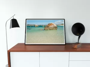 A landscape photo print of a sun-kissed Australian beach with red rocks and blue water.