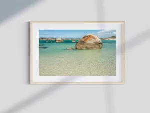 A stunning landscape print of an Australian beach with red rocks and blue water, bathed in the warm glow of the sun.